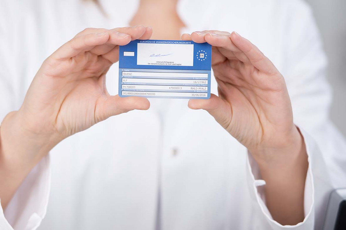 Eine Praxisassistentin hält eine Versichertenkarte in der Hand.