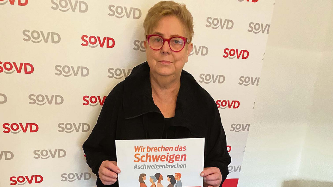 Jutta König hält ein Plakat der Aktion "Wir brechen das Schweigen"