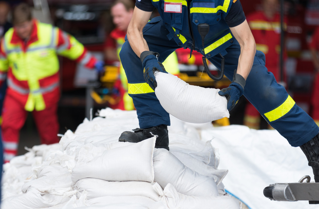 Helfer stapeln Sandsäcke