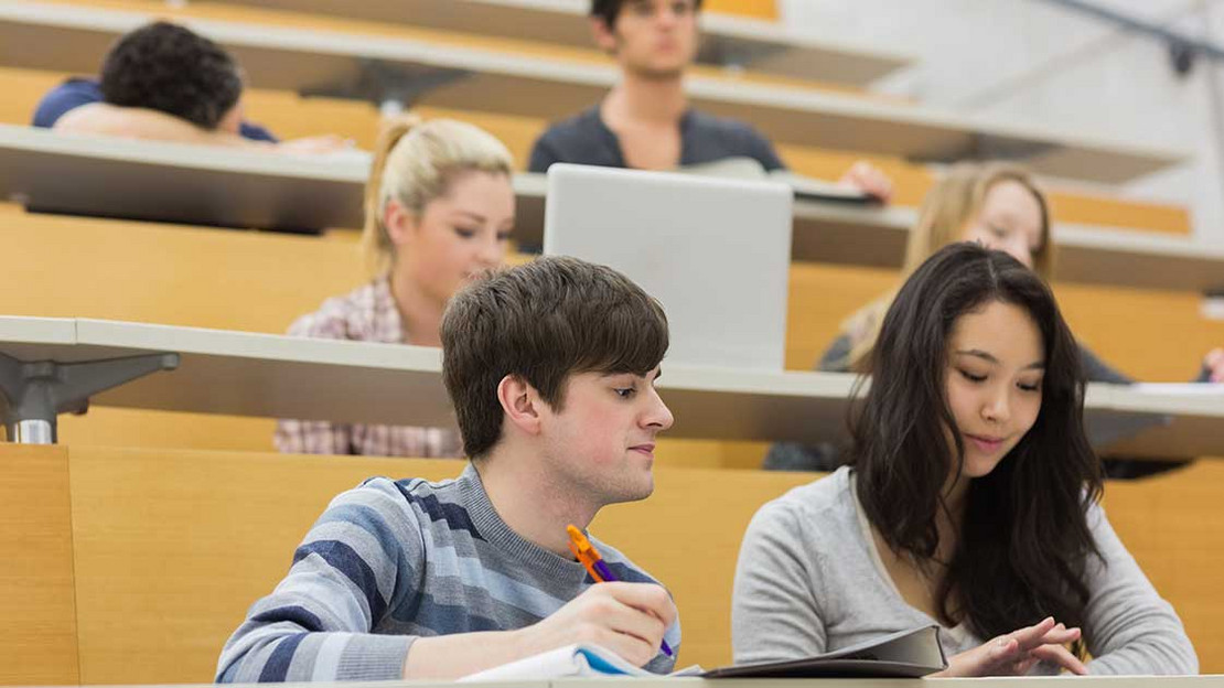 Mehrere Studierende sitzen in einem Vorlesungssaal. 