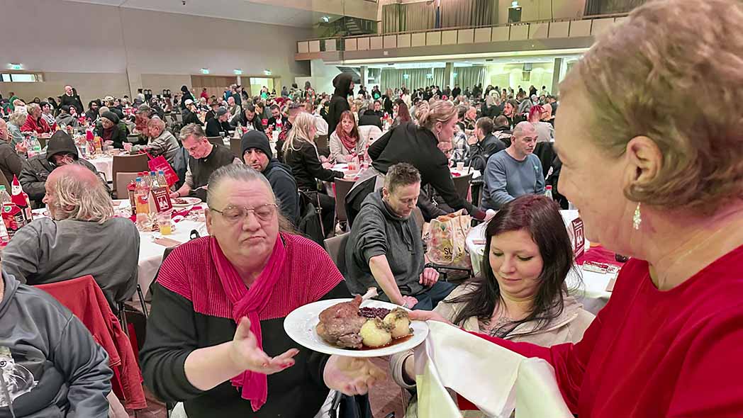 Eine Frau serviert einer anderen Frau einen Teller mit Essen.